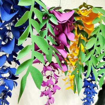 Customizable Colorful Paper Wisteria Garland, with 12 delicately crafted flowers in two sizes, perfect for adding a whimsical touch to celebrations or as a charming home accent.