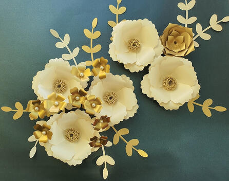 Cream and gold paper flowers, meticulously designed with layers and pearl details, offer a bespoke decorative touch for weddings, celebrations, or everyday elegance."