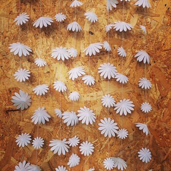 A string of delicately cut white paper flowers in varying sizes, perfect for creating a dreamy ambiance in nursery walls, photo backdrops, or birthday celebrations.
